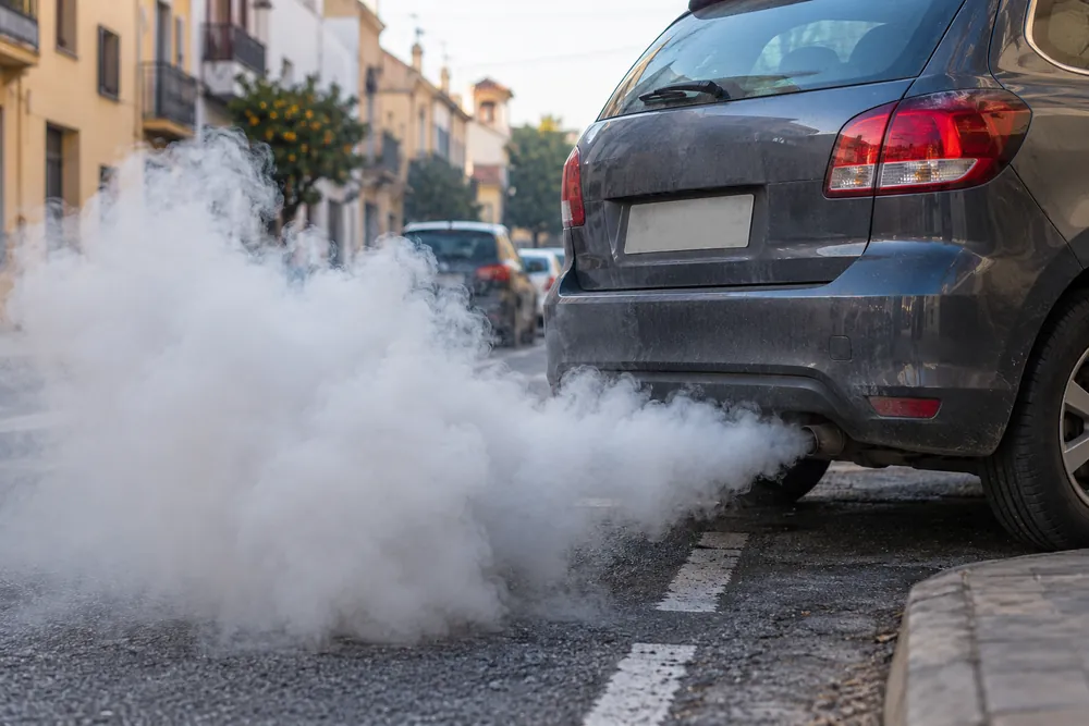 Turismo parado que expulsa una nube de humo denso por el tubo de escape.