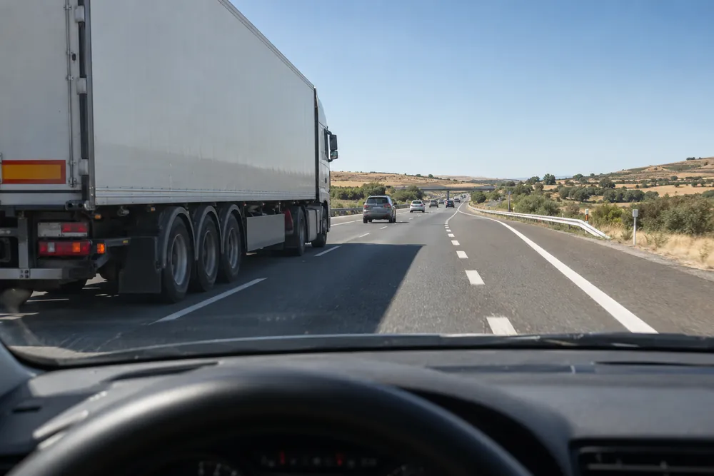 Turismo en el carril de aceleración de una autovía con un camión ocupando el carril derecho.