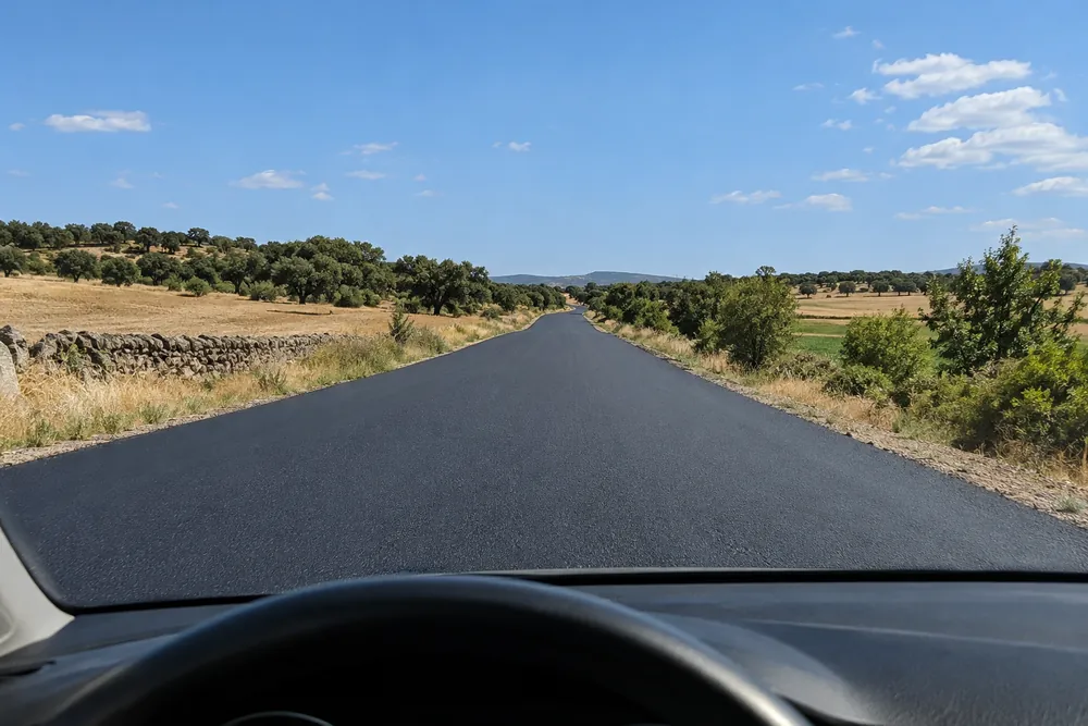Carretera convencional con el asfalto nuevo y sin marcas viales pintadas.