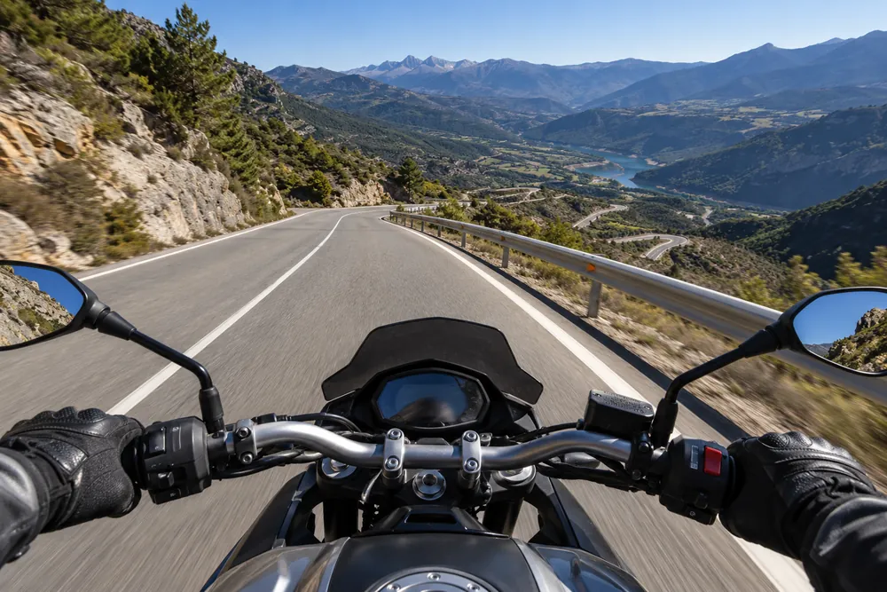 Bajada de un puerto de montaña con curvas vista desde una motocicleta.