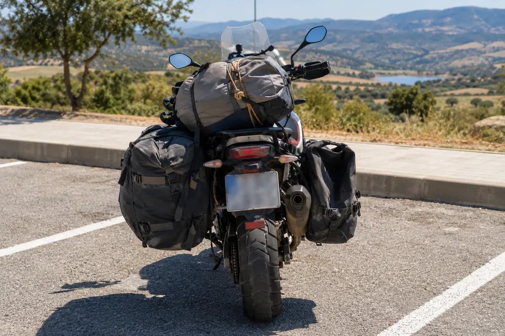 Motocicleta con un bulto voluminoso y unas maletas cargadas de forma desigual en la parte trasera.