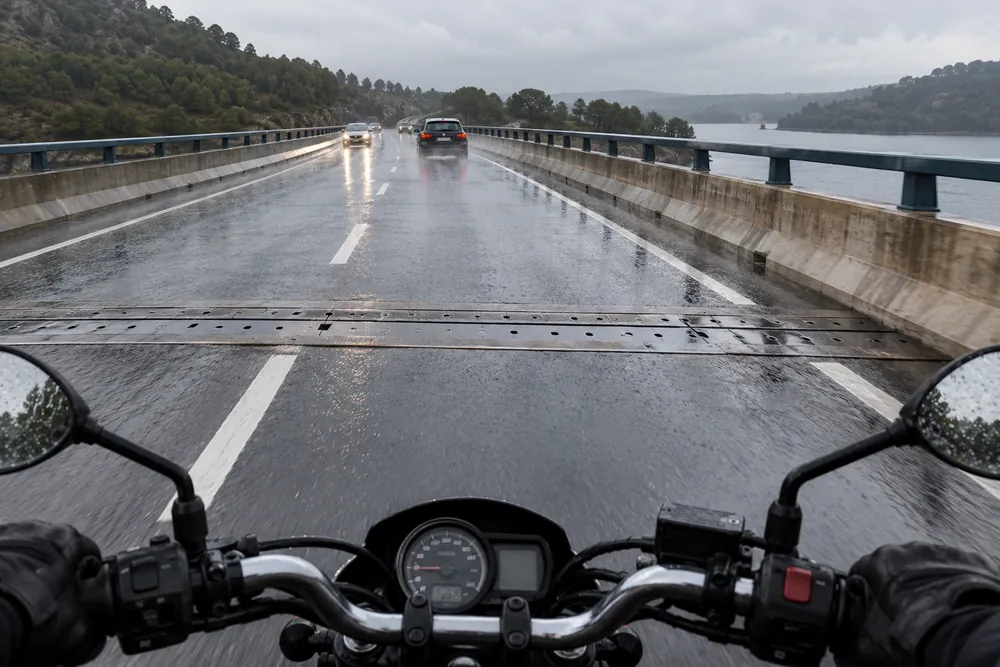 Junta metálica mojada transversal a la calzada vista desde una moto.