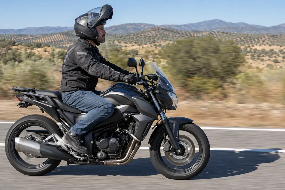 Motorista circulando con un casco modular con la mentonera levantada.