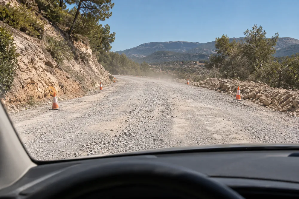 Tramo de carretera en obras con gravilla suelta sobre el firme.
