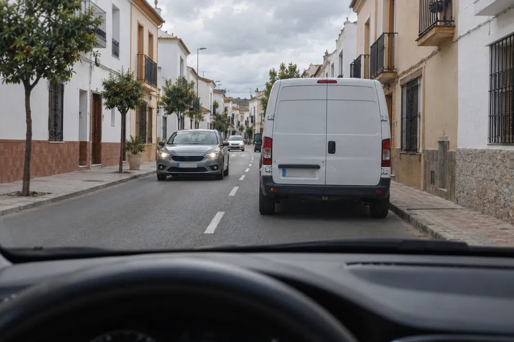 Furgoneta estacionada ocupando el carril propio mientras otro coche se acerca de frente.