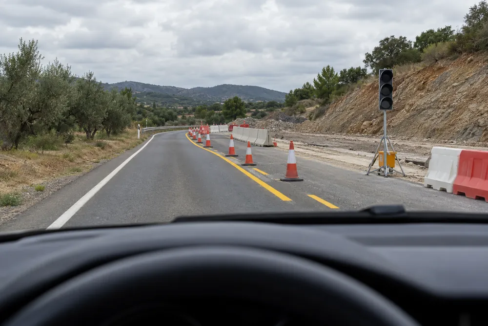 Tramo de obras con un carril cortado y un semáforo provisional apagado.