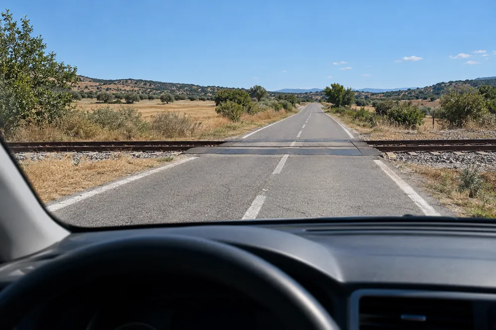 Paso a nivel sin barreras en una carretera rural, con las vías cruzando la calzada.