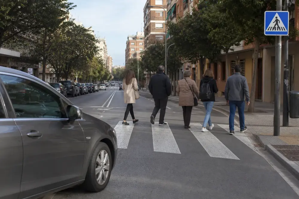Peatones cruzando por un paso de cebra mientras un coche está detenido