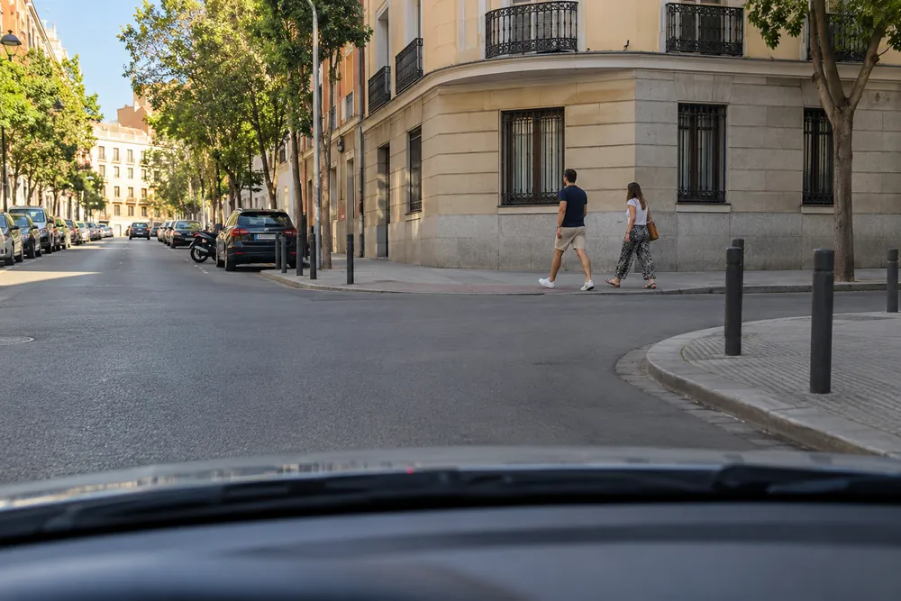 Peatones cruzando una calle sin paso pintado junto a un coche que va a girar.