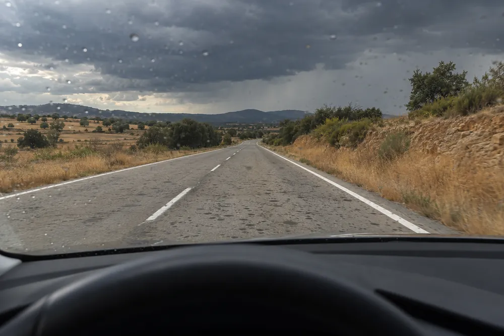Primeras gotas de lluvia sobre una carretera seca y polvorienta.