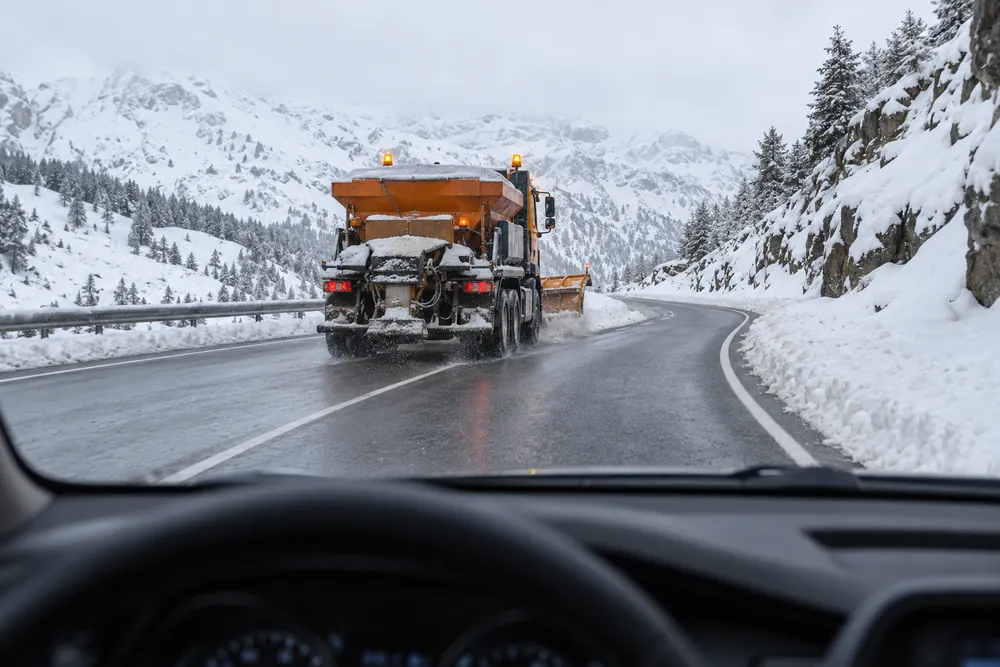 Máquina quitanieves trabajando por delante en un puerto de montaña nevado.