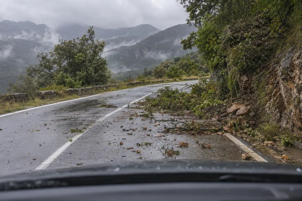 Ramas y piedras sueltas sobre una carretera de montaña tras un temporal.