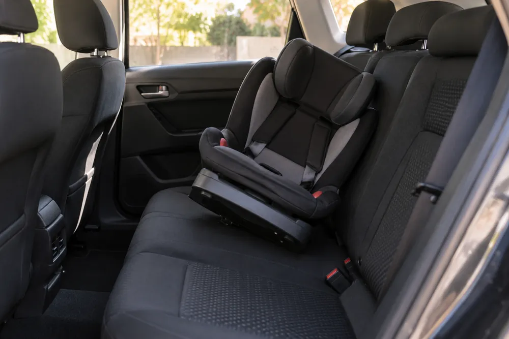 Silla infantil vacía inclinada sobre la banqueta trasera sin fijación visible.
