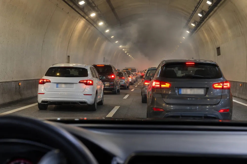 Tráfico detenido dentro de un túnel con humo al fondo.