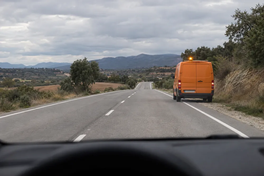 Vehículo de conservación de carreteras circulando despacio con la luz amarilla giratoria encendida.